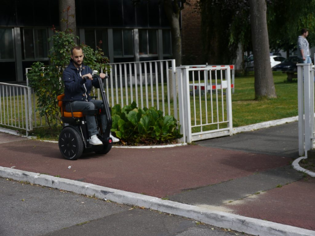 Diapo 5 : Personne se déplaçant dans la rue dans un fauteuil Gyrolift, en position assise.