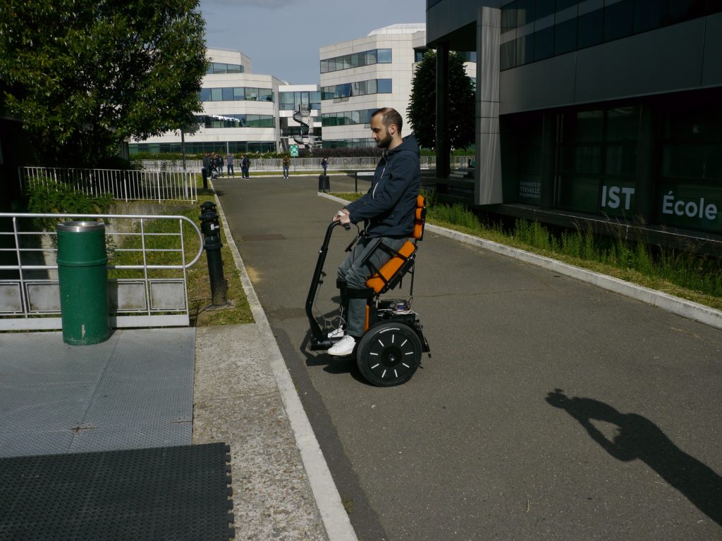 Diapo 2 : Personne se déplaçant dans la rue dans un fauteuil Gyrolift, en position debout.