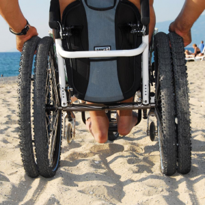 Fauteuil roulant à roues larges, roulant sur du sable.