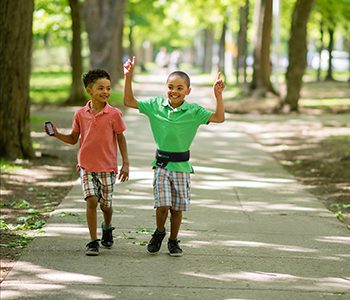 Diapo 3 : Deux enfants marchant dans un parc, l'un d'eux porte une ceinture Navibelt.