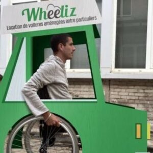 Photo d’un home en fauteuil roulant dans une voiture en carton Wheeliz