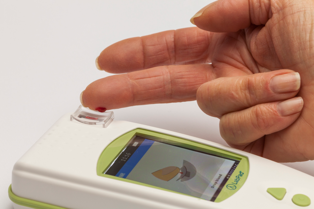 Diapo 4 : Personne effectuant un test sanguin en appuyant son doigt sur un appareil LabPad.