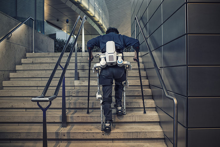 Diapo 3 : Personne montant des escaliers grâce à l'exosquelette H-MEX.