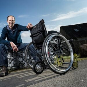 Homme assis à côté d’un fauteuil roulant qui dispose de la roue forcewheel