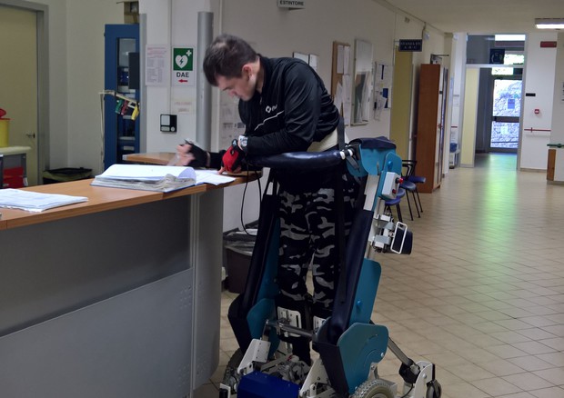 Diapo 3 : Homme en position debout sur le fauteuil Rise, signant un document