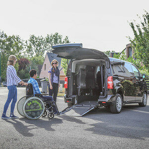 Photo d’un véhicule adapté aux personnes en fauteuil roulant avec un homme en fauteuil qui monte dans le véhicule