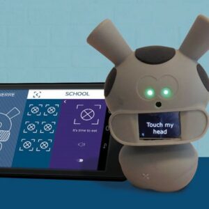 Photo du robot Mwoo avec écrit dessus « touche ma tête », avec derrière l’application sur une tablette