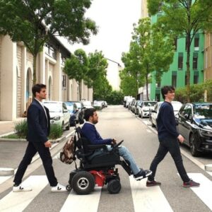 Les trois fondateurs d’Andyamo traversant sur un passage piéton avec Marco tétraplégique en fauteuil roulant