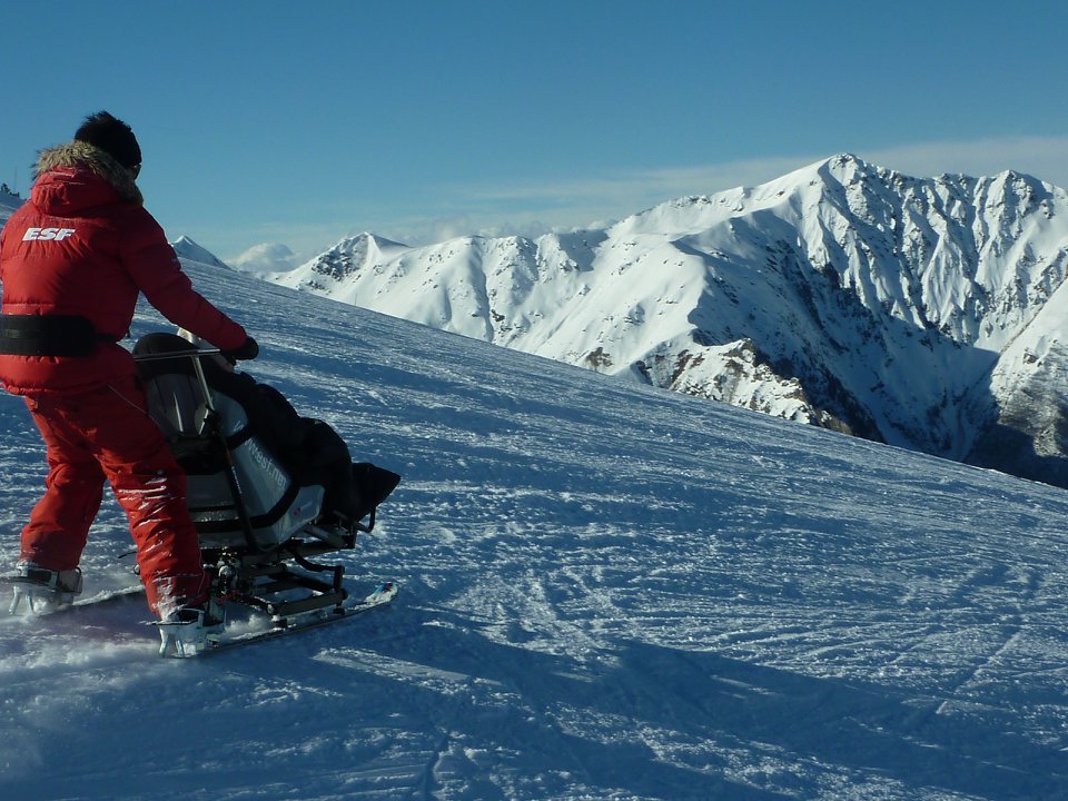 Diapo 3 : Moniteur de ski qui aide une personne à mobilité réduite à skier