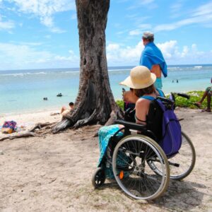 Femme en fauteuil roulant sur le sable au bord d’une plage