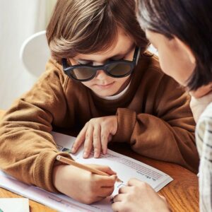 Photo d’un garçon qui écrit tout en portant les lunettes Lexilens