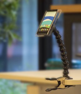 Un bras articulé de handieasy avec un smartphone accroché sur une table