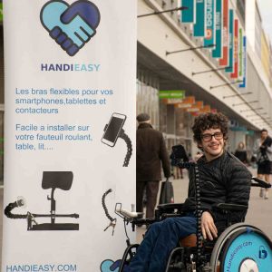 Jason Chemama dans son fauteuil et face à son kakémono de son entreprise Handieasy