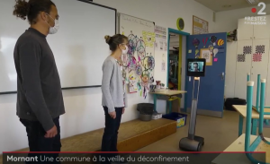 Deux personnes dans une classe devant un tableau avec le robot Awabot utilisé par quelqu'un de chez soit