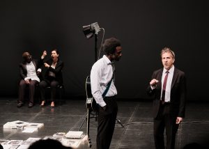 Deux comédiens au premier plan jouant leur pièce de théâtre avec en second plan deux interprètes LSF