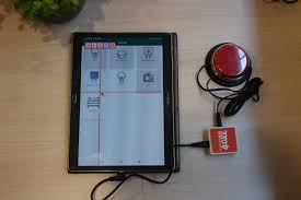 Diapo 4 : Une tablette android avec l'application Mouse4All, un contacteur rouge et le boitier de Mouse4all sur une table blanche