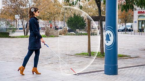 Diapo 2 : Femme qui utilise le dispositif Rango sur une canne blanche détectant un obstacle et son rayon de proximité