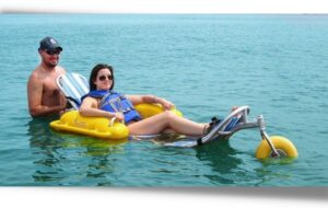 Deux personnes à la mer dont une femme à mobilité réduite sur un fauteuil roulant de plage