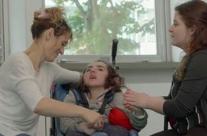 Diapo 4 : Photo d'une petite fille handicapée testant le dispositif tactilaptic avec deux femmes