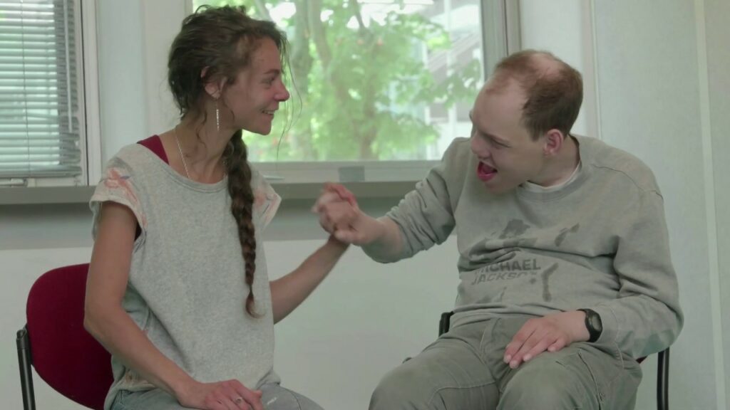 Diapo 2 : Image d'une personne en situation de handicap qui touche la main d'une femme, les deux personnes sourient