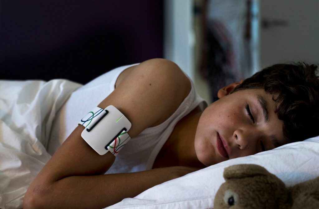 Diapo 2 : Photo d'un enfant qui dort avec le bracelet NightWatch autour de son bras