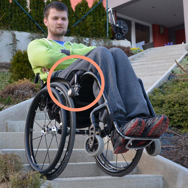 Diapo 2 : Homme sur un fauteuil roulant en équilibre dans des escaliers, avec le frein DEZZIV sur sa roue